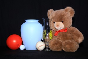 Still life lit with on-camera lighting with three balls, two vases, and a Teddy bear. There are nearly no shadows.