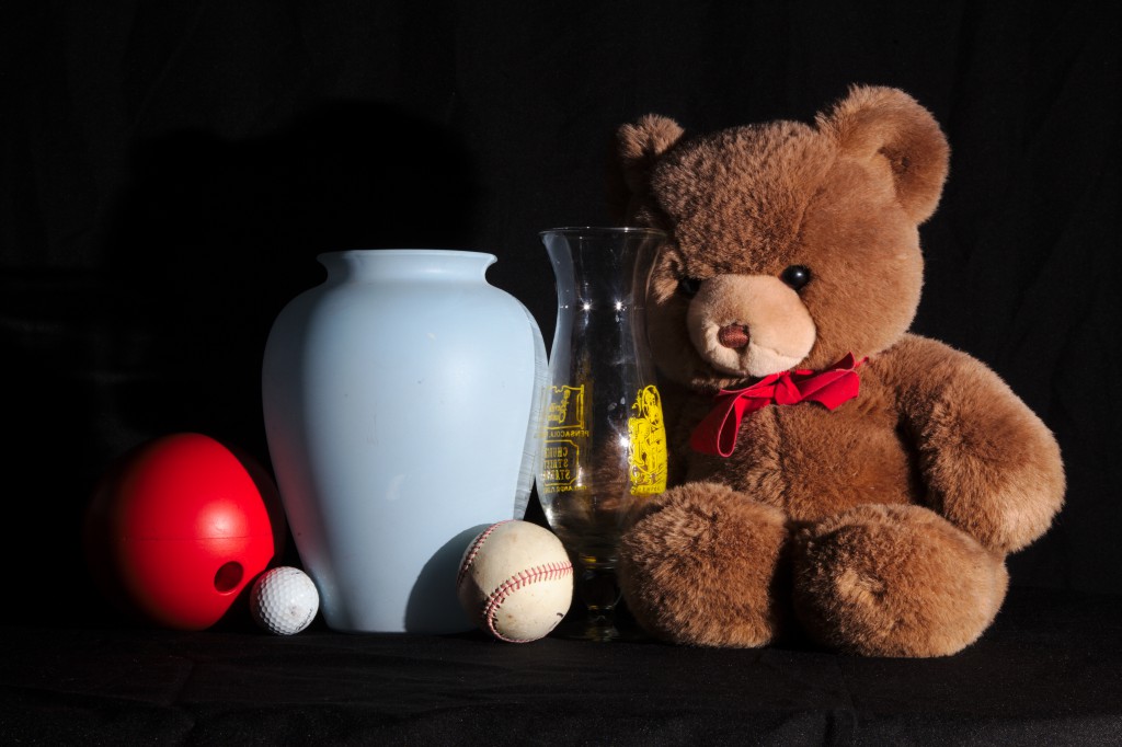 Front-45 degree lighting for a still life with three balls, two vases, and a Teddy bear. Shadows show the shape of objects.